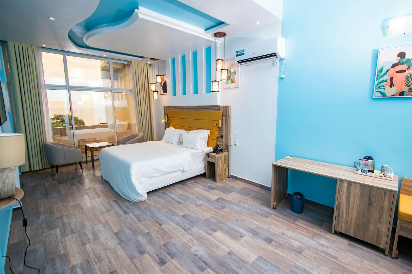 Pokój hotelowy z łóżkiem queen size i dwoma szarymi fotelami.